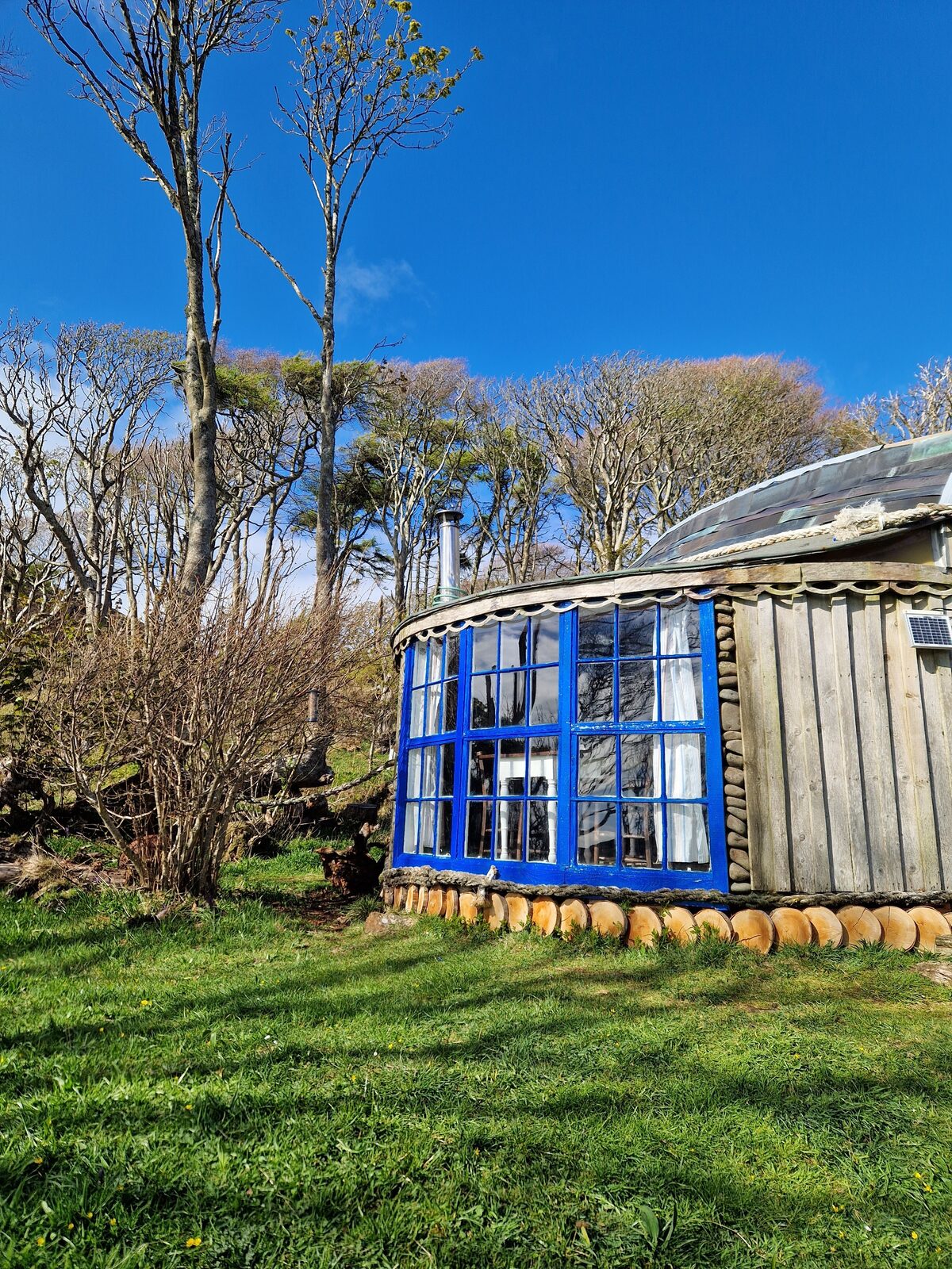 The curved blue window bay with timber cladding and boat-scale roof against a clear sky